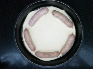 4、满园春色香肠披萨,醒好的面团，排气后，铺在披萨盘底部。放上珍妮珍馐罗勒烤肠。