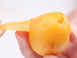 2、蜜渍枇杷,用刀切掉枇杷的蒂，然后就可以一片一片撕开枇杷的外衣了。