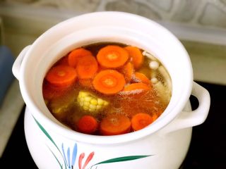 9、暖心排骨汤,20分钟之后，放入水果玉米和胡萝卜，继续小火加盖炖煮20分钟；