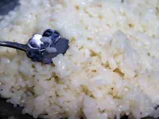 4、芒果糯米饭,趁热把一半的椰浆牛奶液倒入米饭上，用勺子搅拌均匀，使米饭均匀吸收到椰浆。