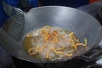 2、清迈面,拍上面粉的面条入油锅炸至金黄。