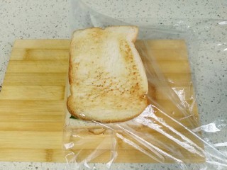 10、三明治,最后加盖土司片。保鲜膜压实裹紧三明治。