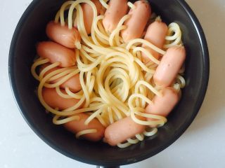 4、咖喱芝士热狗意面,把煮好的意面沥水，平铺到碗底；