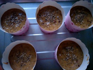 11、#家有烤箱#＋低卡红枣糕,烤箱预热180度，放进蛋糕纸杯，撒上芝麻