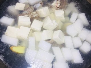 4、#懒人料理#双玉骨头萝卜汤,双玉嘛，肯定少不了豆腐的存在，把豆腐切块放进去。