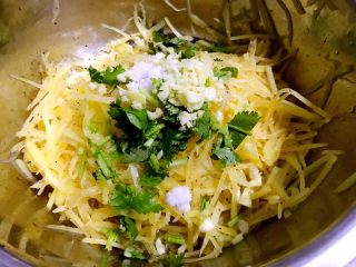 6、凉拌麻辣土豆丝,土豆丝放入容器中放入盐、味精、糖、辣椒油、麻油、米醋、香菜段、蒜粒