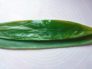 5、蜜枣西米粽子,两张粽叶，叶柄相对，光面朝上，重叠在一起；