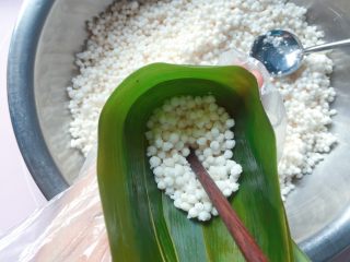 7、蜜枣西米粽子,在漏斗中舀入1/3的西米，拿筷子轻轻捅实。