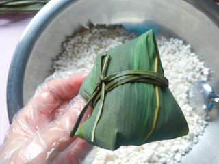 12、蜜枣西米粽子,用绑粽绳在粽腰处扎紧打结，一个紧实漂亮的粽子就包好啦。