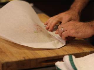 6、双色西葫芦烤龙利鱼,烘焙纸离边缘0.6厘米处开始向内部折叠，折得紧一些，形成半月形。边折边压，使纸包尽可能地封得紧一些。不然的话蒸汽会漏掉。