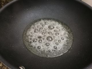 5、#家常菜大比拼#陈皮炒年糕,锅里放少许水加热，放入冰糖慢慢化开，一边搅动，到水分基本收干就可以了（我们不是要做拔丝，所以把糖化开，水分收一些，如图这样泡泡咕嘟咕嘟就差不