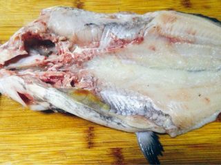 9、香辣烤鱼,将处理干净的鱼鱼肚朝上，用斩刀由鱼肚开口处将鱼头斩成两瓣（可先用剪刀将鱼下颚剪开），然后用刀顺鱼骨将鱼剖开（背部相连），鱼尾相连，然后在鱼背改花刀。