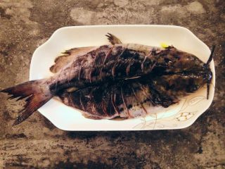 10、香辣烤鱼,取一个葱段，适量姜片切丝均匀铺在鱼盘底部，鱼正反面均匀抹上盐后平铺在葱姜丝上，淋上料酒腌制约10分钟。