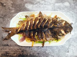 20、香辣烤鱼,将烤好的鱼移入鱼盘，鱼背向上铺放在炒好的菜上面。