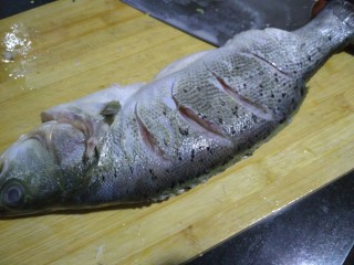 2、柠檬烤鲈鱼,鱼身切几刀，鱼肚子切开，一会儿要把鱼爬在烤盘上，把盐抹在身上，腌半个小时