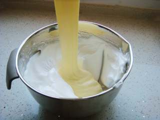 9、红枣戚风蛋糕杯,把打好的蛋白分一半倒入蛋黄糊糊里。呈“J”字形翻拌，不可划圈避免消泡。翻拌均匀后倒入剩下的蛋白中。