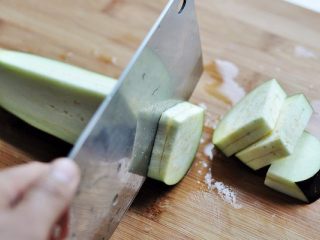 4、香煎茄盒,紧贴着再切一刀,第二刀要切透茄子,切成两片底部相连的茄子夹,方便夹入肉馅。