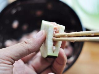 6、香煎茄盒,把腌渍好的肉馅塞进茄子夹中,抹匀后用手按压使之凭证匀实。依次把剩余的茄子夹都塞入肉馅。