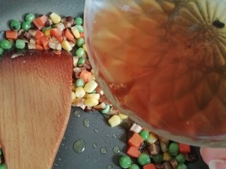 4、海苔什锦炒饭,翻炒一小会后倒入泡香菇的水，继续翻炒直青豆断生。