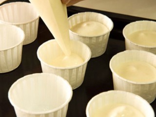 12、柠檬戚风小蛋糕,将做好的蛋糕糊装入裱花袋，挤入事先准备好的小纸杯中（提示:挤入纸杯的蛋糕糊只填充五、六分满）