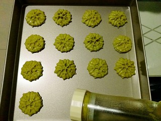 11、抹茶曲奇饼干,装上雪花片模具,将曲奇饼一个一个压在华福不粘烤盘上,注意留间距