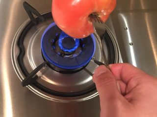 2、灵魂番茄炒蛋,首先我们先把番茄去皮，用叉子固定番茄根部，煤气开小火，用火焰顶端烘烤番茄，中途不断旋转方向；