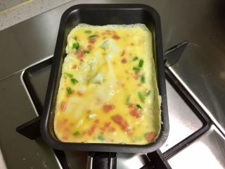 4、香葱火腿厚蛋烧,玉子烧锅刷一层油,烧热,保持小火慢煎,倒入部分蛋液,煎成蛋皮。