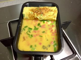 8、香葱火腿厚蛋烧,然后倒入蛋液煎第三层蛋皮。