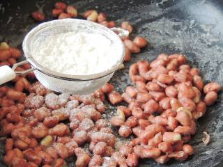 9、花生粘,待糖汁包裹住花生米，边翻炒边筛入干淀粉