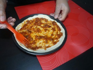 12、独家秘制香肠披萨,用勺子，在披萨饼底部。涂抹均匀即可。