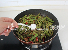 9、干煸四季豆,调入盐和一点点白糖，继续翻炒至水汽完全收干即可出锅。