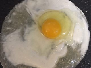 4、鸡蛋灌饼,打一整个鸡蛋在饼上，盖锅盖。因为该饼特薄，故放入饼后确认不粘锅即可打鸡蛋；香肠同时在锅内加热