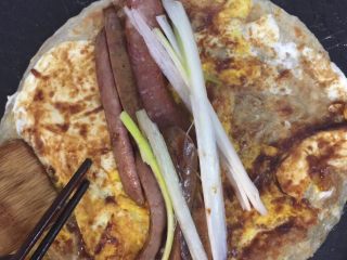6、鸡蛋灌饼,觉得鸡蛋已熟时将饼翻转，加入甜面酱（或其他酱类），抹均匀，加入香肠、葱白等