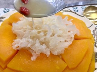19、#吉祥年菜#金银满屋福满仓~椰香南瓜蒸银耳,将南瓜盘里蒸出的蜜汁加入17步骤的碗里，把没有融化的椰子粉尽量搅拌融化，然后舀上蜜汁淋再银耳上