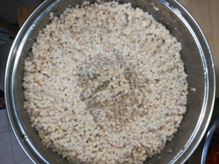 6、酒麸,边搅拌边加入凉白开,搅拌均匀稍微湿润即可,在麦仁中间挖个小坑,倒入少许凉白开。