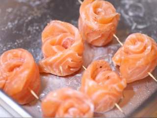 5、低温三文鱼,将两片三文鱼卷成卷用牙签穿起