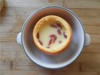 11、国橙蒸枸杞蛋,撒干净的枸杞子进去，包上保鲜膜（我是盖上橙盖子，最好是：表面包上保鲜膜，牙签扎几个洞）。