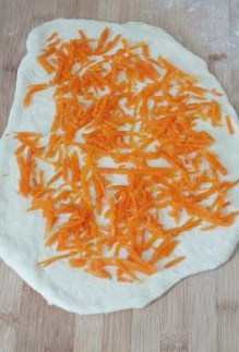 5、【胡萝卜咸面包】,然后再次的将面卷擀薄，上面铺满胡萝卜丝。