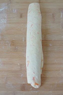 8、【胡萝卜咸面包】,竖着卷起面片。