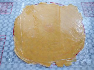 12、椰香南瓜派,面团取出，上下垫一层保鲜膜，用擀面杖擀成一张大饼皮，要比派盘直径大一圈