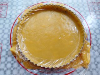 13、椰香南瓜派,揭掉一层保鲜膜，把饼皮慢慢的放到派盘上，多余的部分按压保鲜膜就可以轻松的去掉了，多余的饼皮可以用来烤饼干