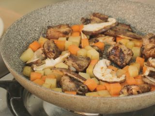 2、什锦排骨焖饭,将胡萝卜丁、土豆丁、香菇倒入，翻炒3分钟。