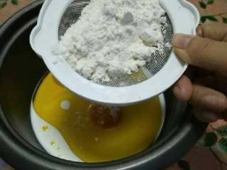 9、家庭烤箱自制戚风蛋糕,开始做蛋黄糊，筛入低筋面粉，用手动打蛋器或者四根筷子顺时针搅拌直到无颗粒，