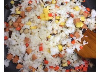 3、五彩扬州炒饭#健康美颜餐#,锅内加入白米饭、玉米热狗肠粒、菠萝粒翻炒，待米粒松散。