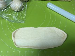 8、圣诞花环面包,松弛好的面团按扁，擀成椭圆，一边长边刻意擀薄一点便于粘合