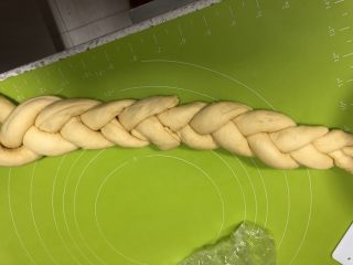 11、圣诞花环面包,把3条面卷头部捏合，像编辫子一样编起来，另外三条从尾部粘上继续编