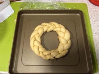 12、圣诞花环面包,编好的辫子面卷首位捏紧，一定要捏紧哈，以免再次发酵时裂开