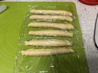 9、圣诞花环面包,从长边卷起面团，每一份都如此卷好，盖上保鲜膜松弛10分钟