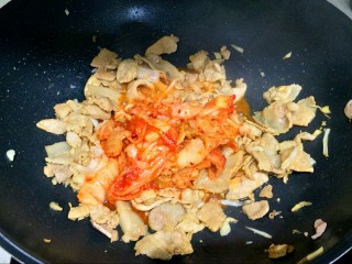 8、辣白菜五花肉,把辣白菜下锅,大火翻炒2分钟,让肉和辣白菜充分融合。