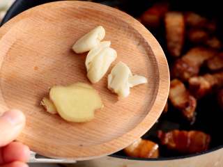 7、红烧肉炖白萝卜,放入拍碎的大蒜。2片生姜翻炒出香味；